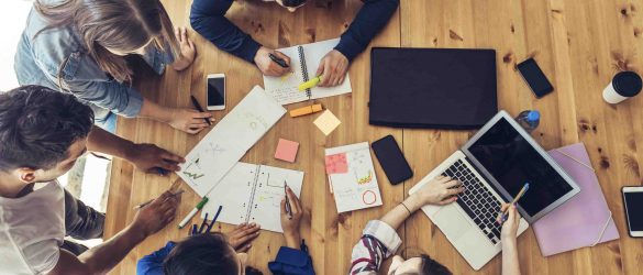 overhead view on young business people around wooden desk